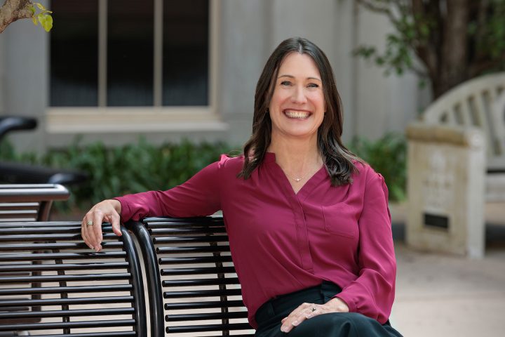 Woman in a garnet blouse seated on a bench.
