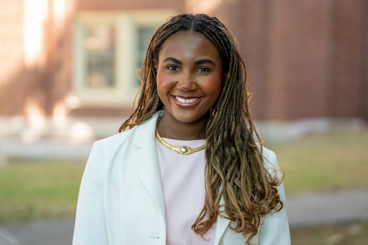 headshot of Black woman with long hair and a light suit