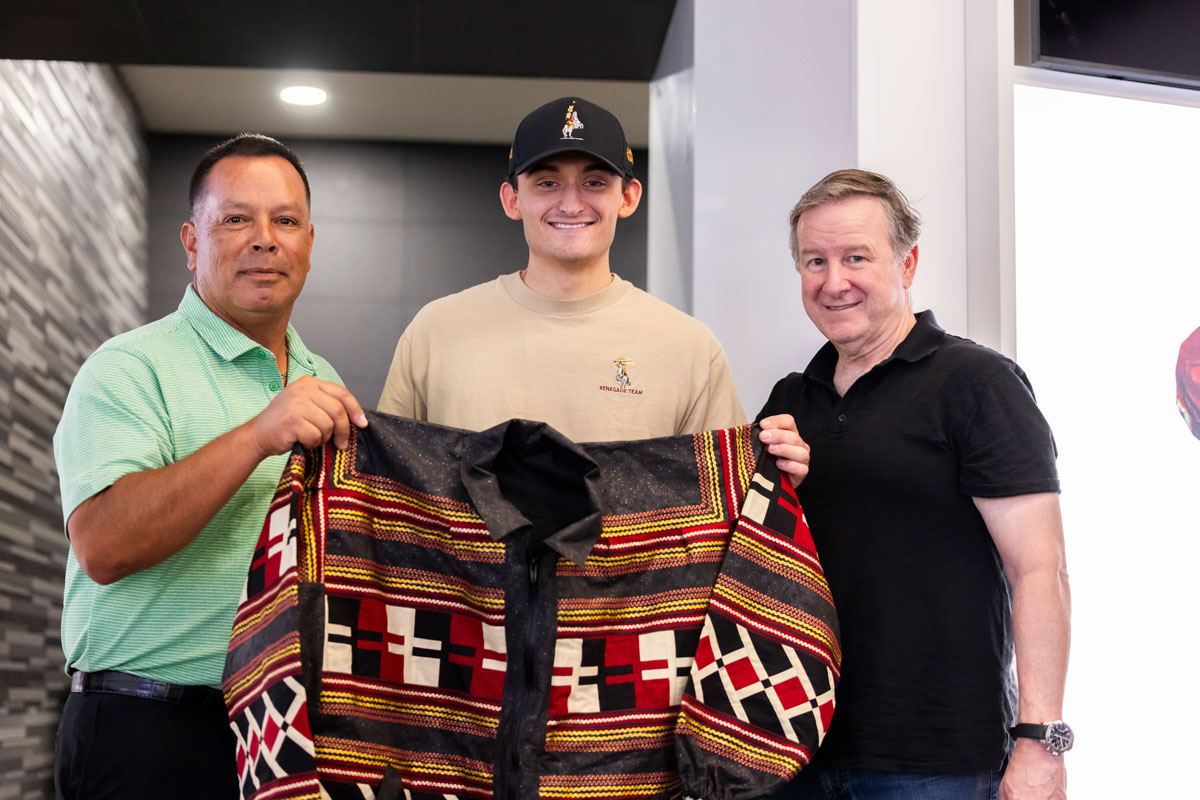 Seminole Tribe Chairman presenting patchwork jacket in FSU locker room