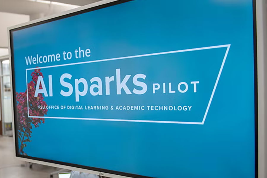 A TV screen displays a welcome slide for the AI Sparks Pilot from FSU's Office of Digital Learning and Academic Technology