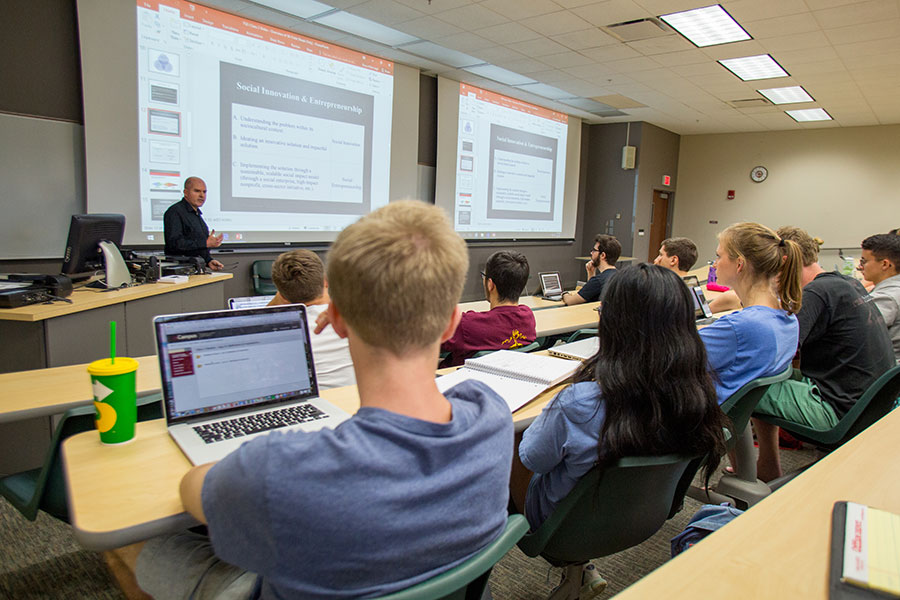 A faculty mentor gestures while speaking to a group during a design thinking workshop