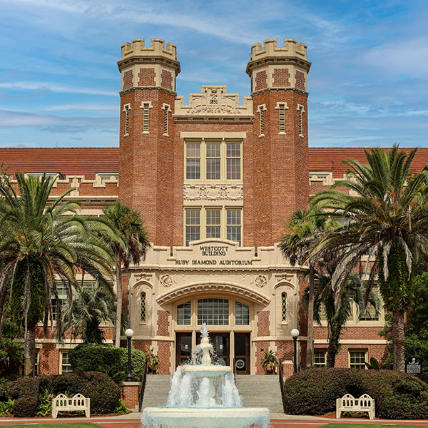 The Westcott Building at Florida State University, a brick and stone academic building, framed by palm trees and a fountain in front