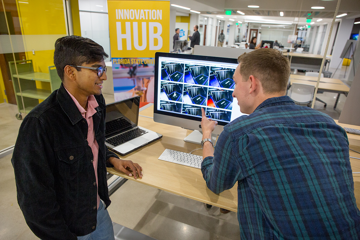 Students collaborating around a computer monitor in an open workspace