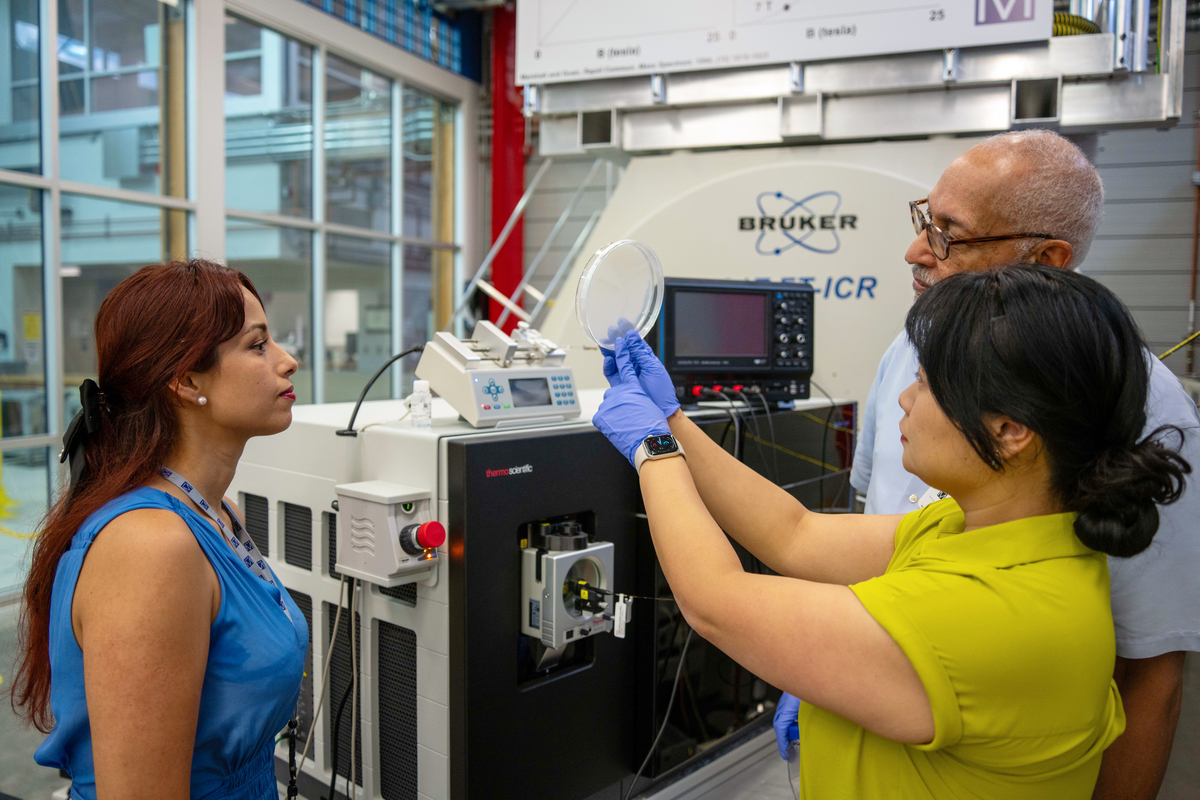 Researchers examining a sample dish in a laboratory setting with specialized scientific equipment
