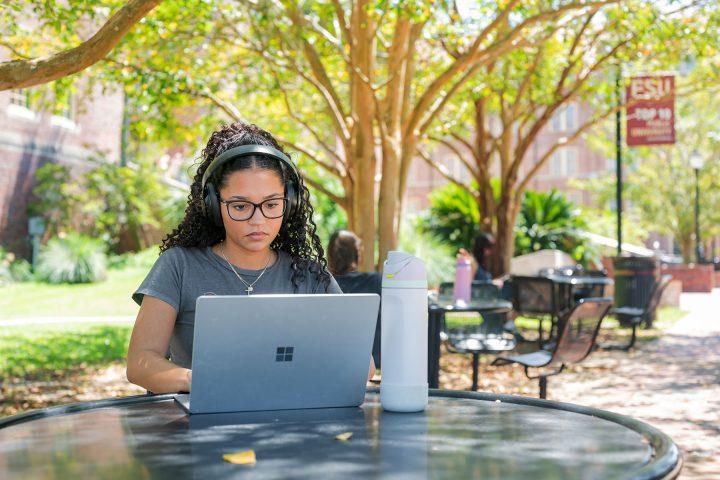 student with headphones on a laptop