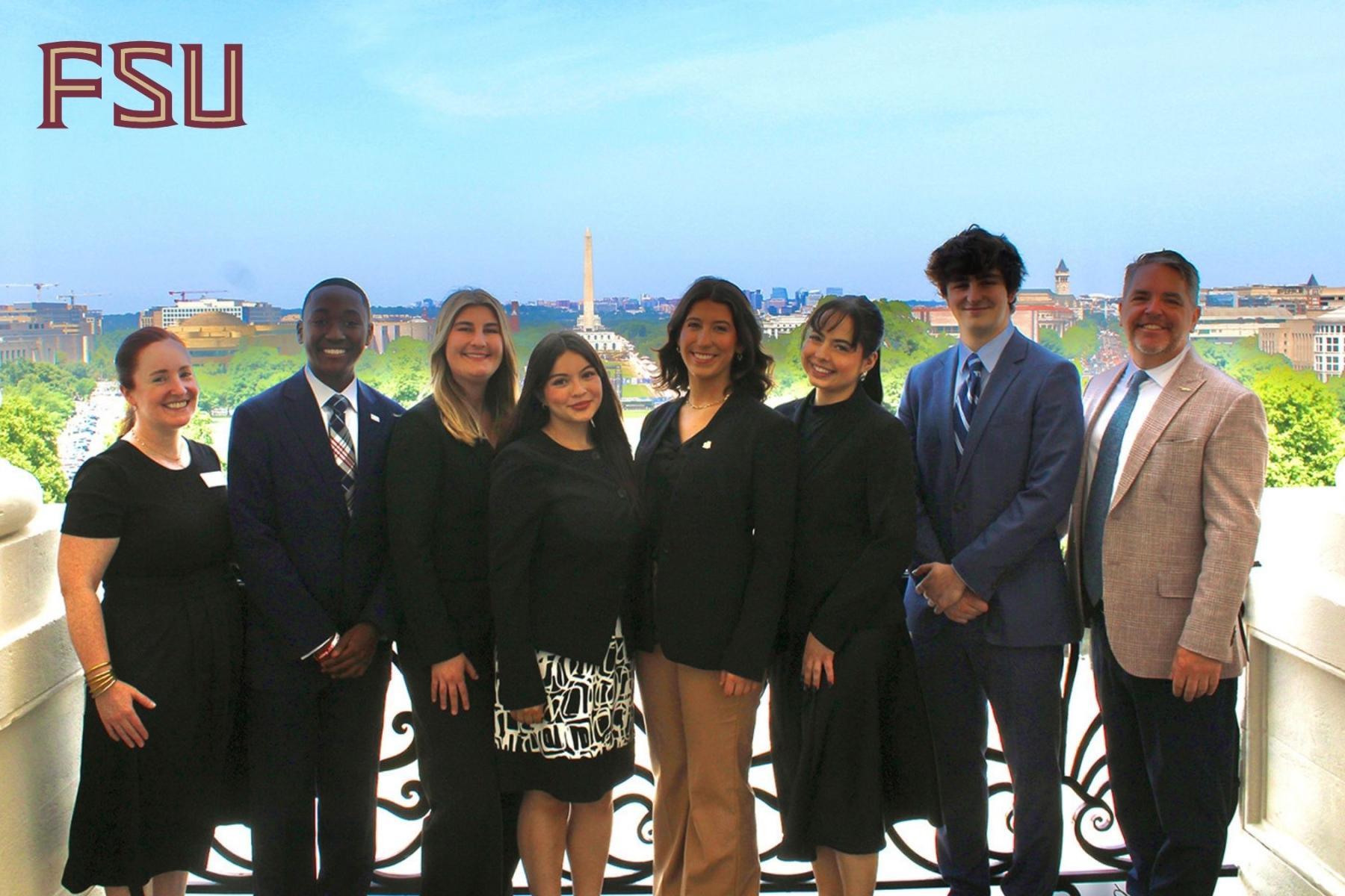 Eight FSU students in business attire pose in a line with the Washington Monument in the background.